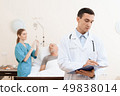man lies on a cot. Doctor and a nurse help him. 49838014