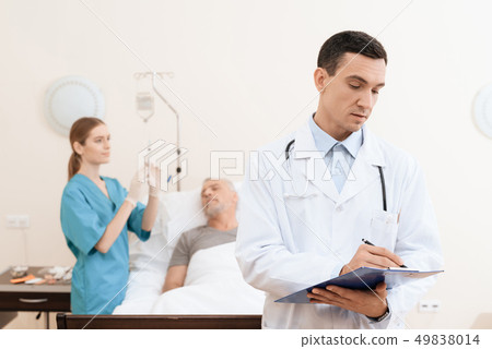 man lies on a cot. Doctor and a nurse help him. 49838014