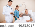man lies on a cot. Doctor and a nurse help him. 49838017