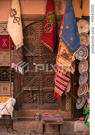 Wooden old Historical door surrounded with Hanging carpets on street of Marrakesh City, Morocco 49842006