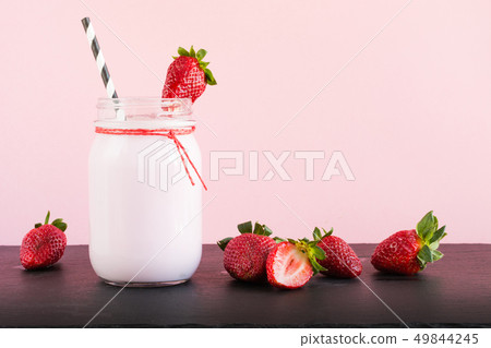 Strawberry milkshake with berry in mason jar on pink. Close up. Summer drink. Strawberry milkshake with berry in mason jar on pink. Close up. Summer drink. 49844245