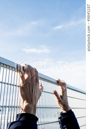 man climbing up a metal fence 49845287