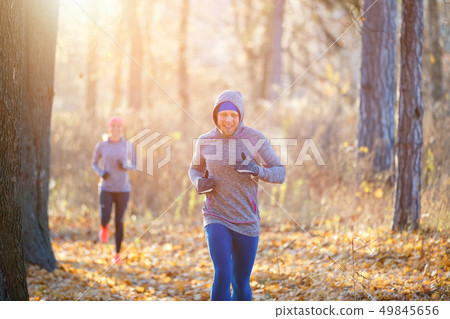 Young man and woman jogging on park trail 49845656