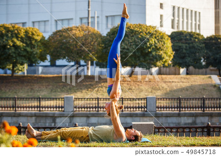 Couple of young man and woman practicing acro yoga Couple of young man and woman practicing acro yoga 49845718