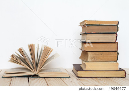 An open book next to a stack of vintage books on a 49846677