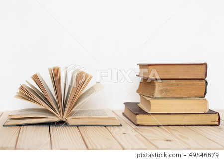 An open book next to a stack of vintage books on a 49846679