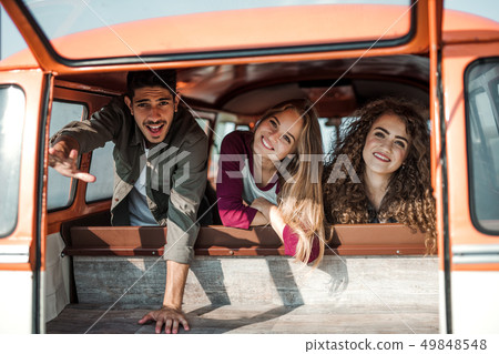 A group of young friends on a roadtrip through countryside, looking out of window. A group of young friends on a roadtrip through countryside, looking out of window. 49848548