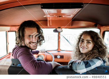 A young couple on a roadtrip through countryside, driving minivan. A young couple on a roadtrip through countryside, driving minivan. 49848551