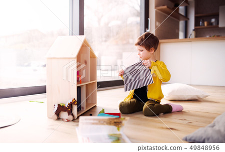 A small girl playing with wooden house on the floor at home. A small girl playing with wooden house on the floor at home. 49848956
