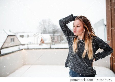 A portrait of young girl or woman with earphones outdoors in winter. A portrait of young girl or woman with earphones outdoors in winter. 49848969