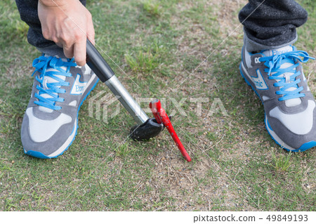 Men pulling out pegs at a campsite Men pulling out pegs at a campsite 49849193