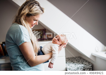 A beautiful young mother with a newborn baby at home. A beautiful young mother with a newborn baby at home. 49849421