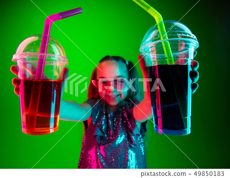 The happy teen girl standing and smiling against green lights background. The happy teen girl standing and smiling against green lights background. 49850183