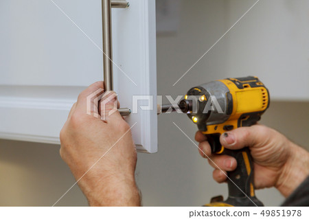 The worker installing handle the white cabinet 49851978