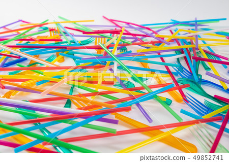 Bright and toxic disposable straws lying with colorful forks 49852741