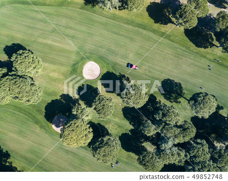 A tractor with loan mower working on a golf course 49852748