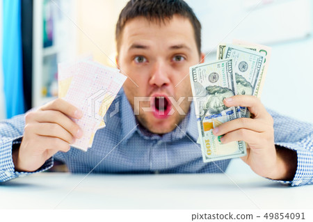 Photo of suprised man with lottery ticket and dollars. 49854091