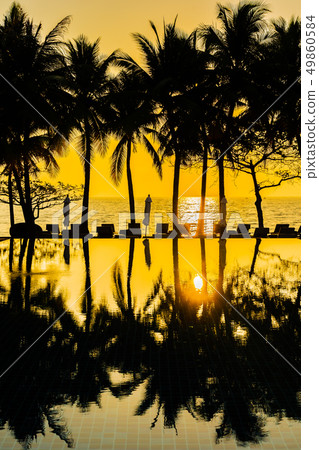 Beautiful Silhouette coconut palm tree on sky around swimming pool in hotel resort neary sea ocean beach at sunset or sunrise time Beautiful Silhouette coconut palm tree on sky around swimming pool in hotel resort neary sea ocean beach at sunset or sunrise time 49860584