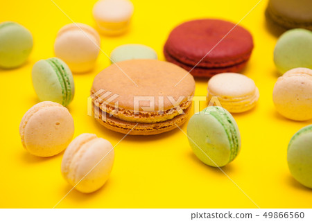 Different patterns of colorful french macaroons on yellow background 49866560