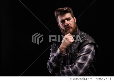 Dramatic portrait of beard man wearing a leather vest over black background Dramatic portrait of beard man wearing a leather vest over black background 49867321