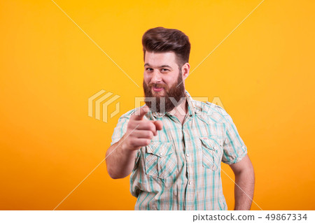 Portrait of bearded man pointing at the camera over yellow background 49867334