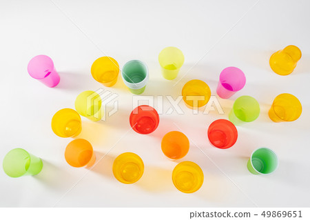Various bright and colorful plastic cups standing on the white surface 49869651