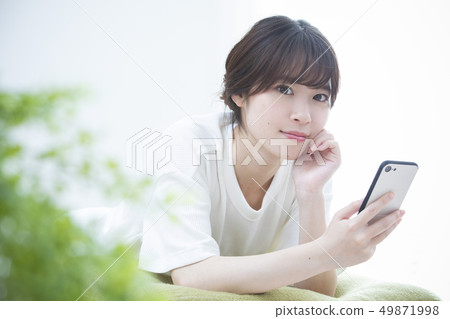 A young woman watching a smartphone A young woman watching a smartphone 49871998