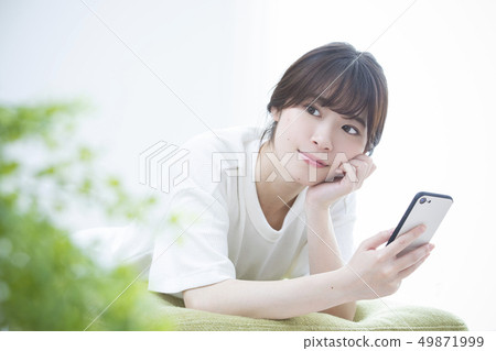 A young woman watching a smartphone A young woman watching a smartphone 49871999