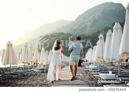 Rear view of family with two toddler children walking on beach on summer holiday. Rear view of family with two toddler children walking on beach on summer holiday. 49876444