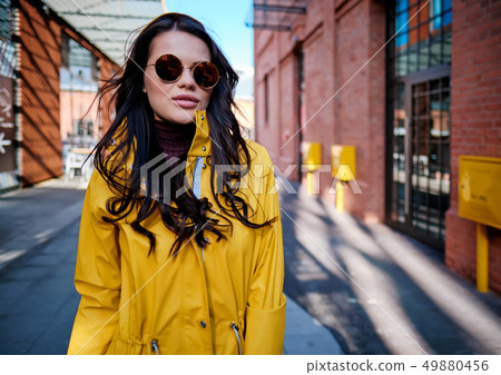 young woman in yellow raincoat at city street young woman in yellow raincoat at city street 49880456