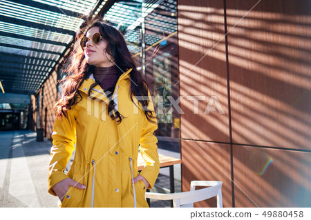 young woman in yellow raincoat at city street young woman in yellow raincoat at city street 49880458