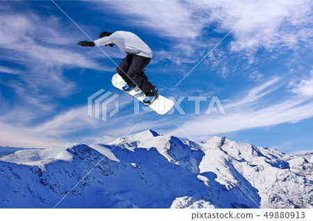 Snowboarder jumping through air with blue sky in Snowboarder jumping through air with blue sky in 49880913