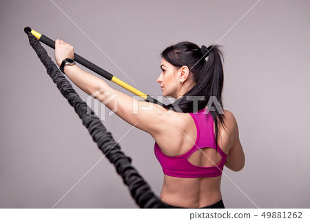 Athletic girl in a purple top and black sports leggings trains with a trainer Rip in the gym Athletic girl in a purple top and black sports leggings trains with a trainer Rip in the gym 49881262