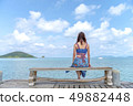 Woman sitting on a chair on the bridge in the sea 49882448