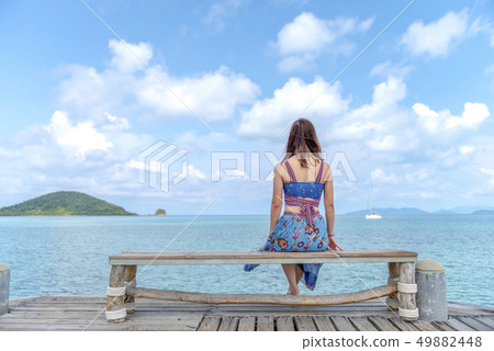 Woman sitting on a chair on the bridge in the sea 49882448