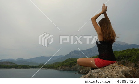 Female tourist sitting on a rock on clear sky and calm sea background 49883429