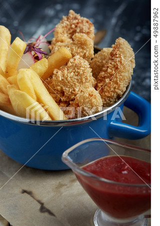 Lunch or snack - fried chicken strips and french fries in a metal pan with tomato sauce. Craft paper Lunch or snack - fried chicken strips and french fries in a metal pan with tomato sauce. Craft paper 49887962