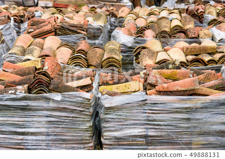 Stacked weathered red roof tiles on ground Stacked weathered red roof tiles on ground 49888131