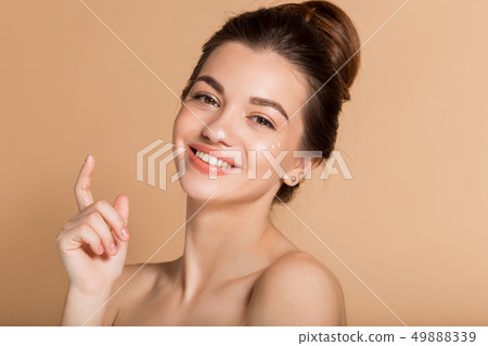 Happy smiling girl with perfect skin with moisturizing face cream on a cheek. Skin care and health Happy smiling girl with perfect skin with moisturizing face cream on a cheek. Skin care and health 49888339