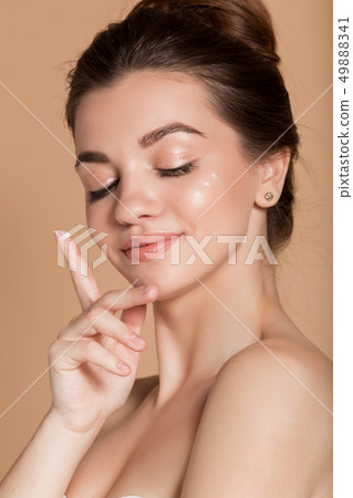 Beautiful face portrait of young woman with perfect skin with moisturizing face cream on a cheek Beautiful face portrait of young woman with perfect skin with moisturizing face cream on a cheek 49888341