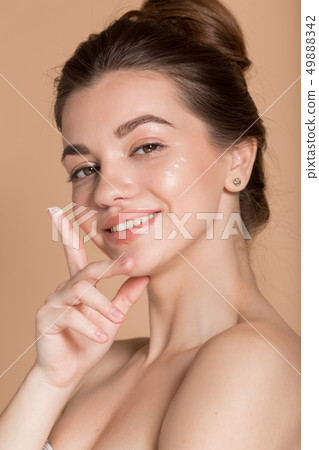Beautiful face portrait of young woman with perfect skin with moisturizing face cream on a cheek Beautiful face portrait of young woman with perfect skin with moisturizing face cream on a cheek 49888342