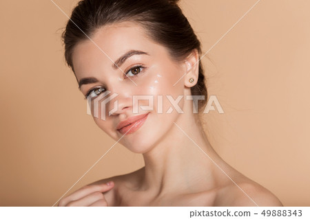 Beautiful face portrait of young woman with perfect skin with moisturizing face cream on a cheek 49888343