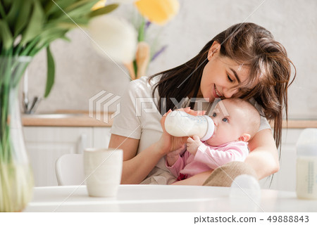 Feeding newborn girl with formula in a bottle. 49888843