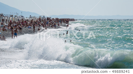 A small storm on the beach, filled with people. 49889241