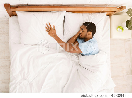Young black guy sleeping innocently in his bed Young black guy sleeping innocently in his bed 49889421