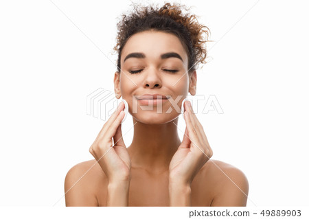 Young woman cleaning her face with cotton pads Young woman cleaning her face with cotton pads 49889903