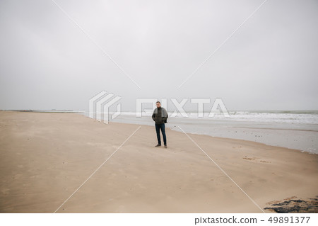 Male tourist walkin along the North Sea. Man with backpack stand on the coast in rainy weather 49891377