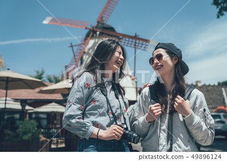 girls looking laughing standing windmill in back 49896124