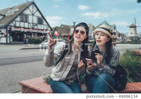 friends consulting online map on phone sitting 49896134