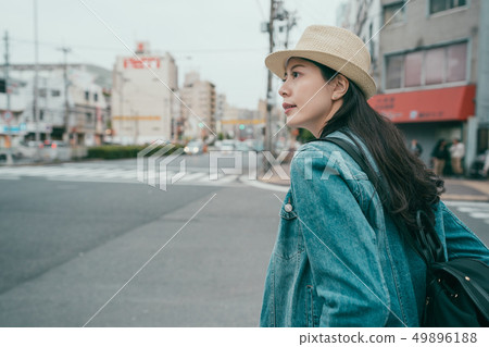 woman in hat with backpack standing on crosswalk 49896188